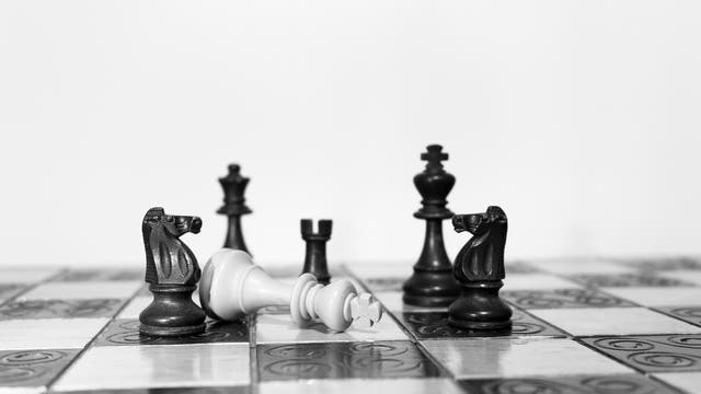 Schachfiguren auf einem Brett: Der weiße König ist gefallen