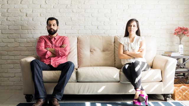 Ein Mann und eine Frau sitzen an verschiedenen Enden eines Sofas und schauen sich nicht an.