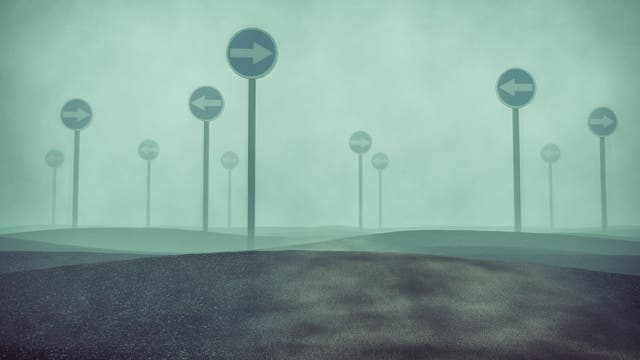 Schilder im Nebel, die in verschiedene Richtungen weisen