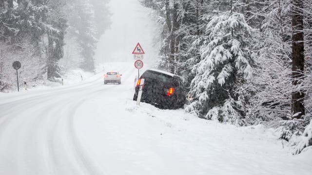 Auf einer schneebedeckten Straße ist ein Auto von der Straße abgekommen. 