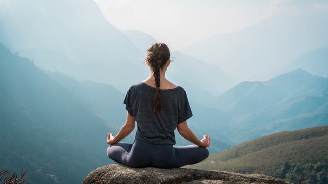 Junge Frau meditiert vor Bergpanorama