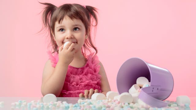 Ein kleines Mädchen kann süßen Marshmallows nicht widerstehen.