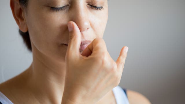 Frau demonstriert Wechselatmung durch die Nase