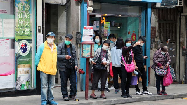 Ältere Menschen warten mit Masken an einer Bushaltestelle in Macau, China, in der Nähe des öffentlichen Krankenhauses.