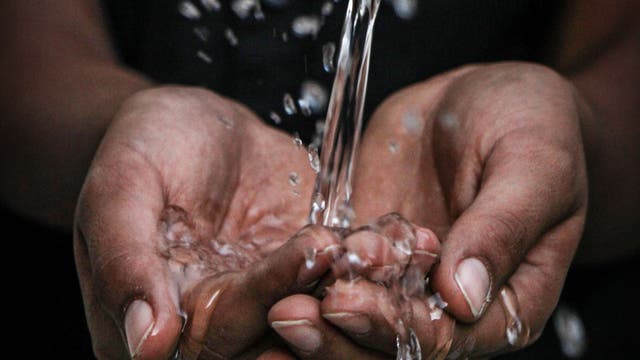 Frisches Trinkwasser perlt auf geöffnete Hände