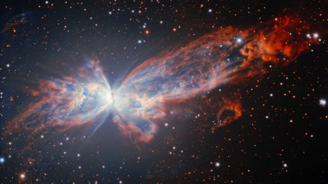 Ein farbenfrohes astronomisches Bild zeigt einen Planetarischen Nebel, der wie ein Schmetterling geformt ist. Die leuchtenden Flügel bestehen aus blauen und orangefarbenen Gaswolken, die sich symmetrisch von einem hellen Zentrum ausbreiten. Der Hintergrund ist mit zahlreichen kleinen, leuchtenden Sternen übersät. Das Bild veranschaulicht die Schönheit und Komplexität kosmischer Strukturen.