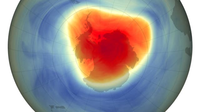 Darstellung der Ozonschicht über der Antarktis, die den Ozonabbau zeigt. Die Karte ist in verschiedenen Farben von Blau bis Rot gehalten, um die Ozonkonzentration in Dobson-Einheiten darzustellen. Der zentrale rote Bereich über der Antarktis zeigt das Ozonloch mit niedrigen Werten unter 220 Dobson-Einheiten an, während die umliegenden blauen Bereiche höhere Ozonkonzentrationen aufweisen. 