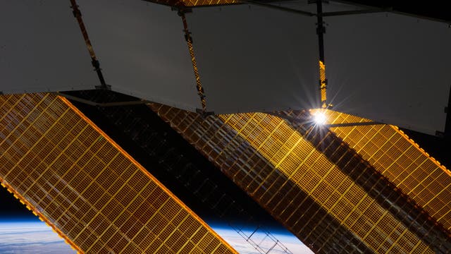 Solarpaneele und Radiator der ISS vor der Erde.