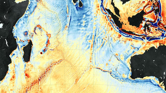 Karte des Bodens des Indischen Ozeans: Sie basiert auf Gravitationsdaten: Rot sind starke Abweichungen nach oben, dunkelblau nach unten. Gut erkennbar sind der Mittelozeanische Rücken links und der Ninetyeast Ridge rechts in der Karte, wo Vulkanismus dichtes Krustengestein erzeugt. In Schwarz sind Landmassen wie Madagaskar abgebildet.