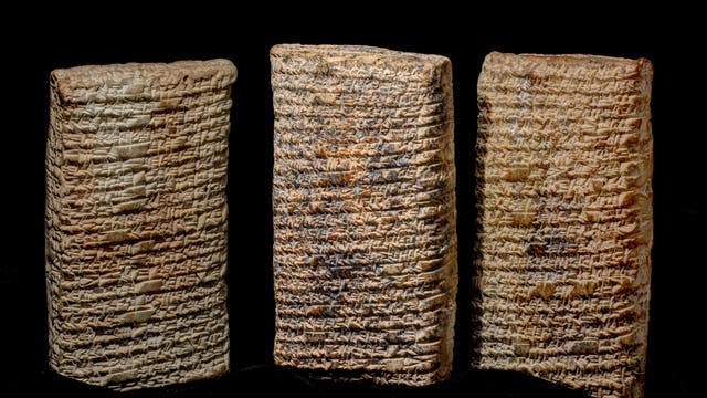 Drei altbabylonische Tontafeln mit Keilschrift, die aufrecht nebeneinander stehen. Die Tafeln sind mit dicht geschriebenen, eingravierten Zeichen bedeckt, die literarische Informationen enthalten. Der Hintergrund ist schwarz, was den Fokus auf die Textur und Details der Tafeln lenkt.