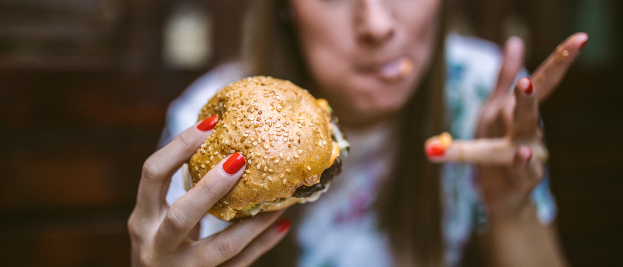 Eine Frau isst mit Genuss einen Burger.