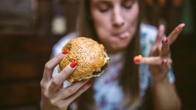 Eine Frau isst mit Genuss einen Burger.