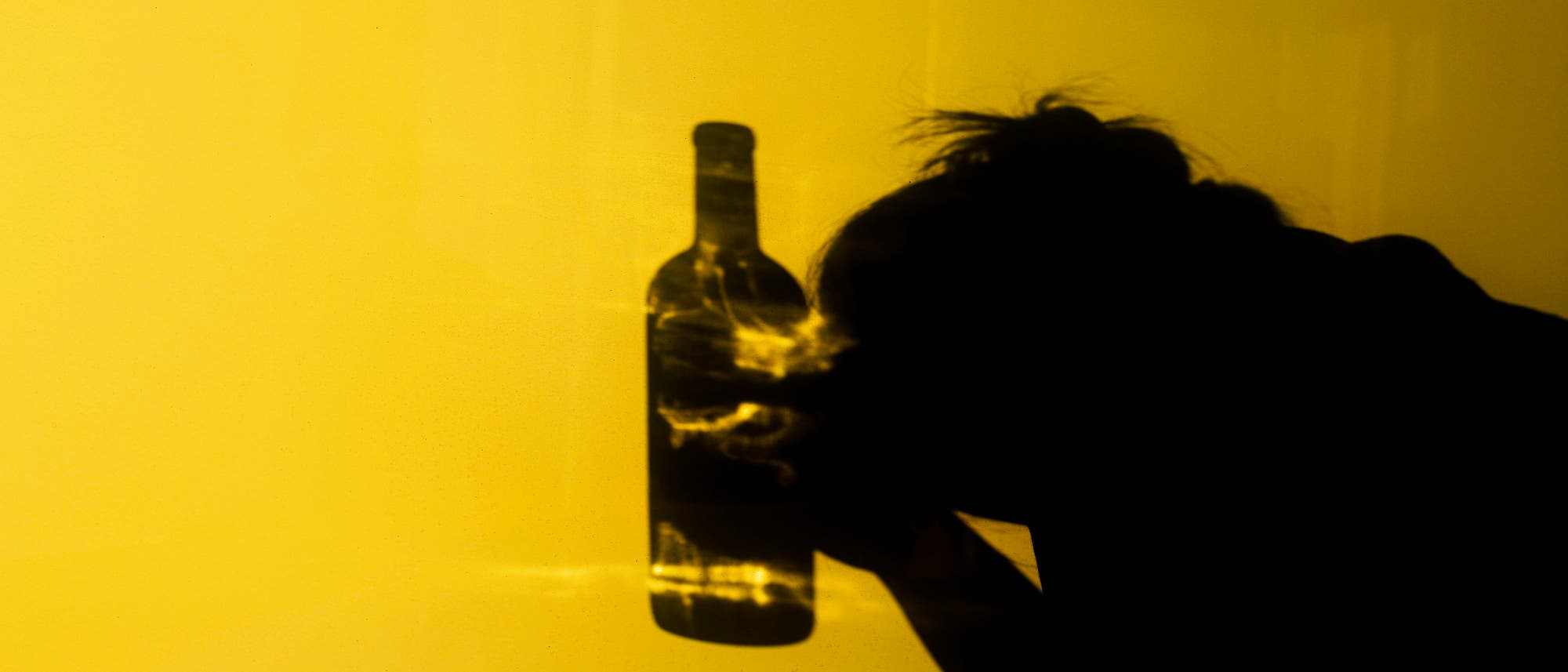 Schatten einer Person, die eine Flasche in der Hand hält. Schatten einer Person, die eine Flasche in der Hand hält.