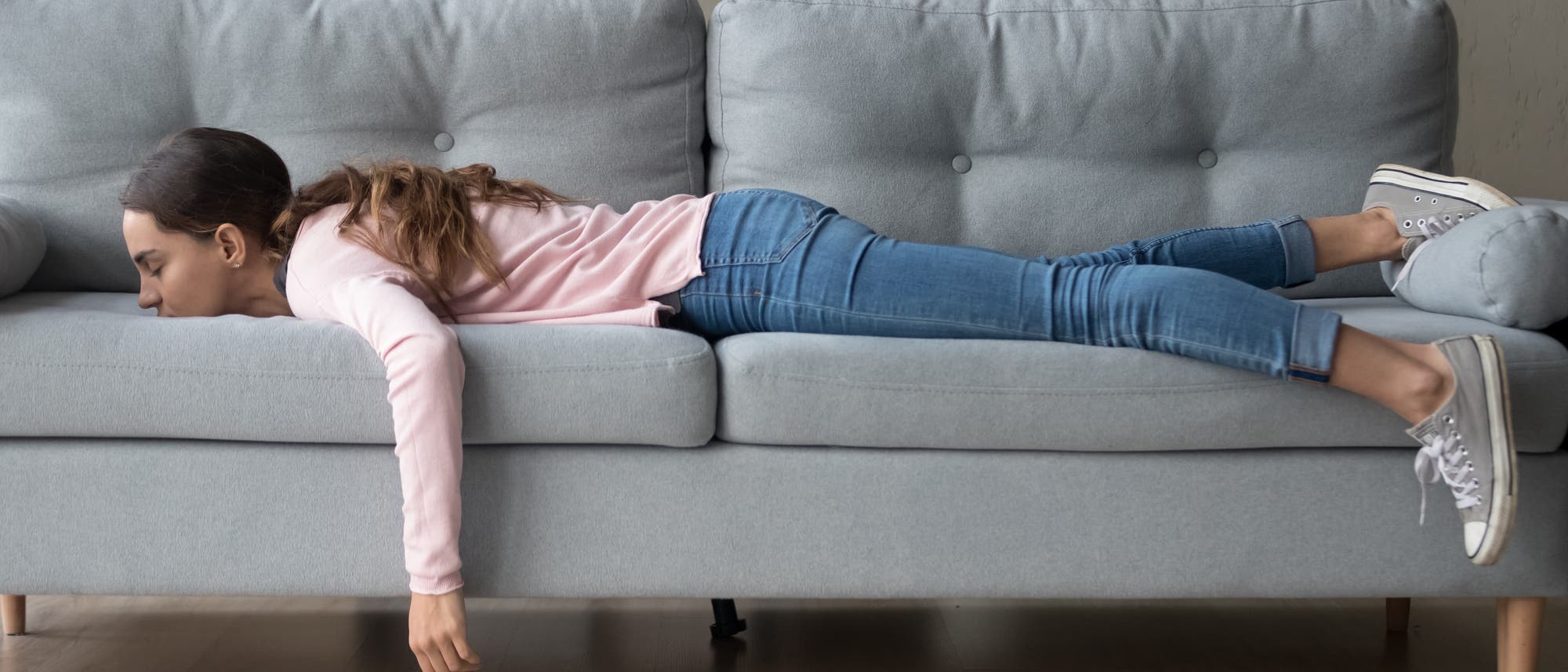 Junge Frau liegt bäuchlings auf dem Sofa und schläft Junge Frau liegt bäuchlings auf dem Sofa und schläft