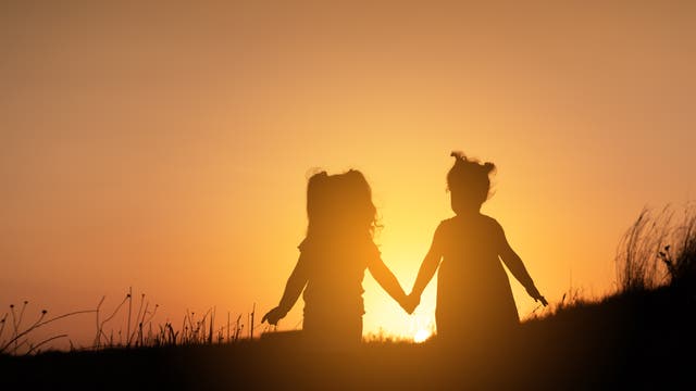 Zwei Kinder im Gegenlicht der untergehenden Sonne.