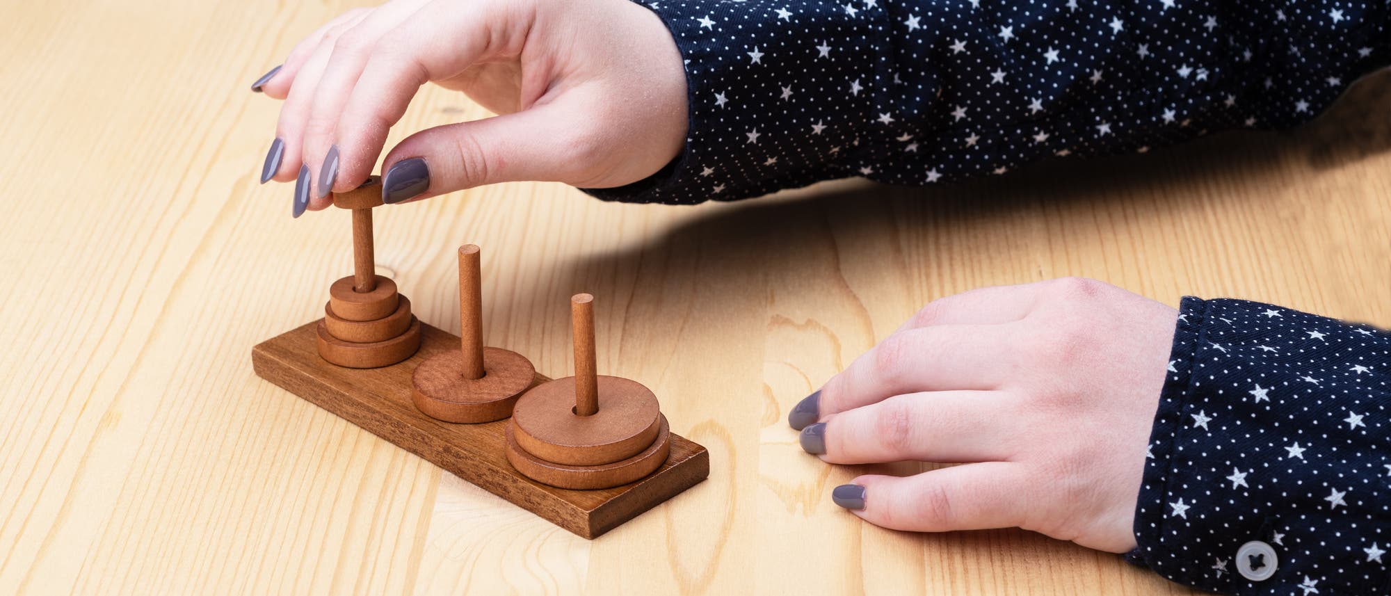Die Hand einer jungen Frau, die Türme von Hanoi spielt. Die Hand einer jungen Frau, die Türme von Hanoi spielt.