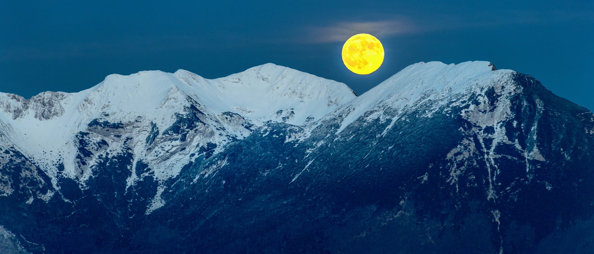 Der vollmond geht über einem schneebedeckten Berggrat auf. Der vollmond geht über einem schneebedeckten Berggrat auf.