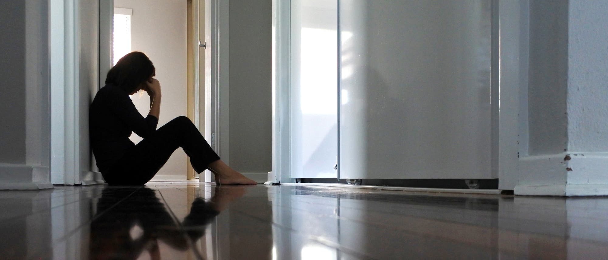 Eine Frau sitzt traurig auf dem Boden im Flur. Ja, das ist ein schlechtes Symbolbild für Depression, aber es gibt keine guten. Eine Frau sitzt traurig auf dem Boden im Flur. Ja, das ist ein schlechtes Symbolbild für Depression, aber es gibt keine guten.