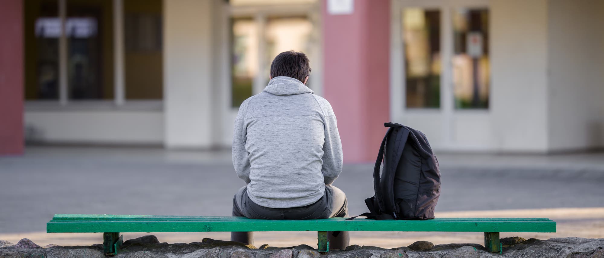 Ein Jugendlicher sitzt auf einer Bank auf dem Schulhof. (Symbolbild) Ein Jugendlicher sitzt auf einer Bank auf dem Schulhof. (Symbolbild)
