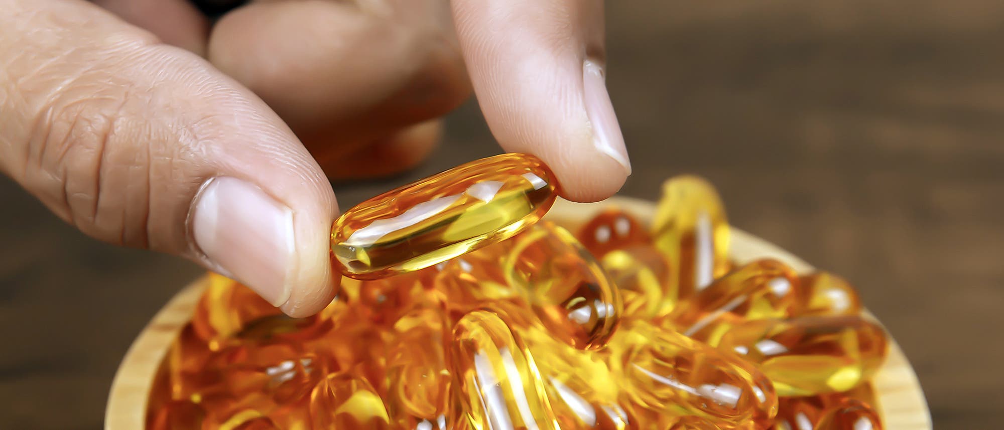 Eine Hand greift nach Vitamin-D-Kapseln Eine Hand greift nach Vitamin-D-Kapseln