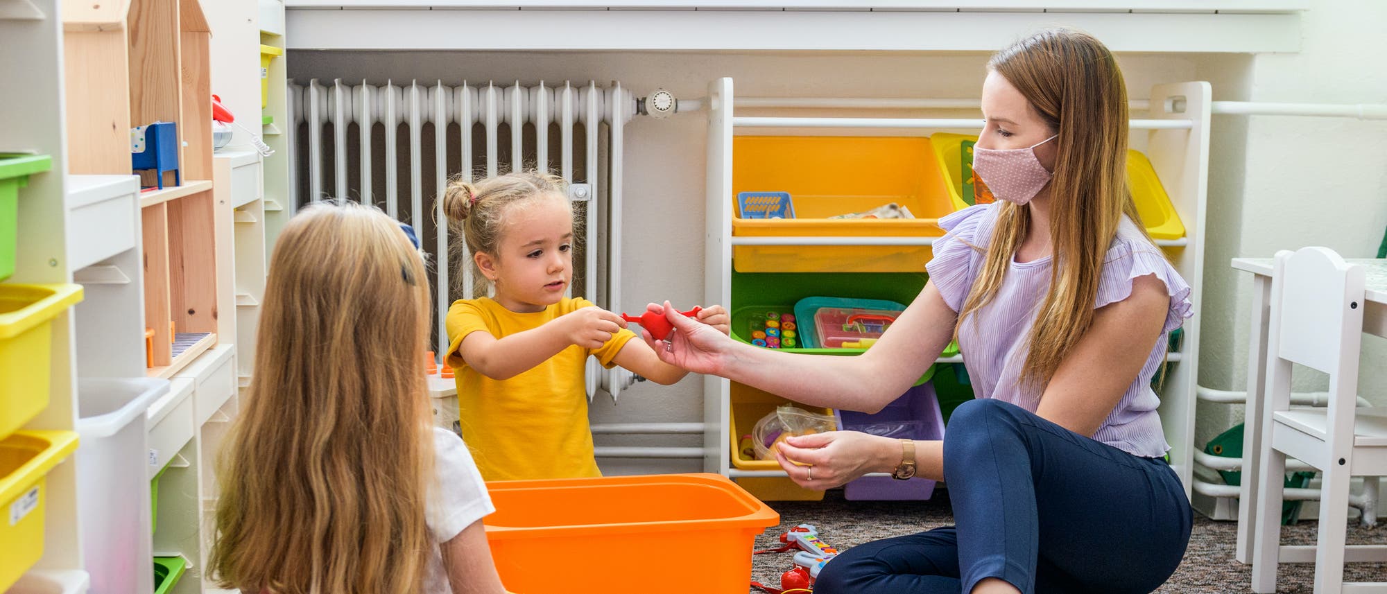 Zwei Mädchen spielen unter Anleitung einer Ergotherapeutin. Zwei Mädchen spielen unter Anleitung einer Ergotherapeutin.