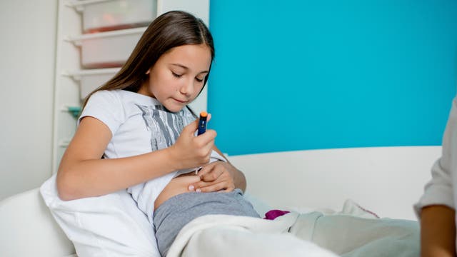 Ein junges Mädchen spritzt sich Insulin mit einem Injektor in den Bauch.