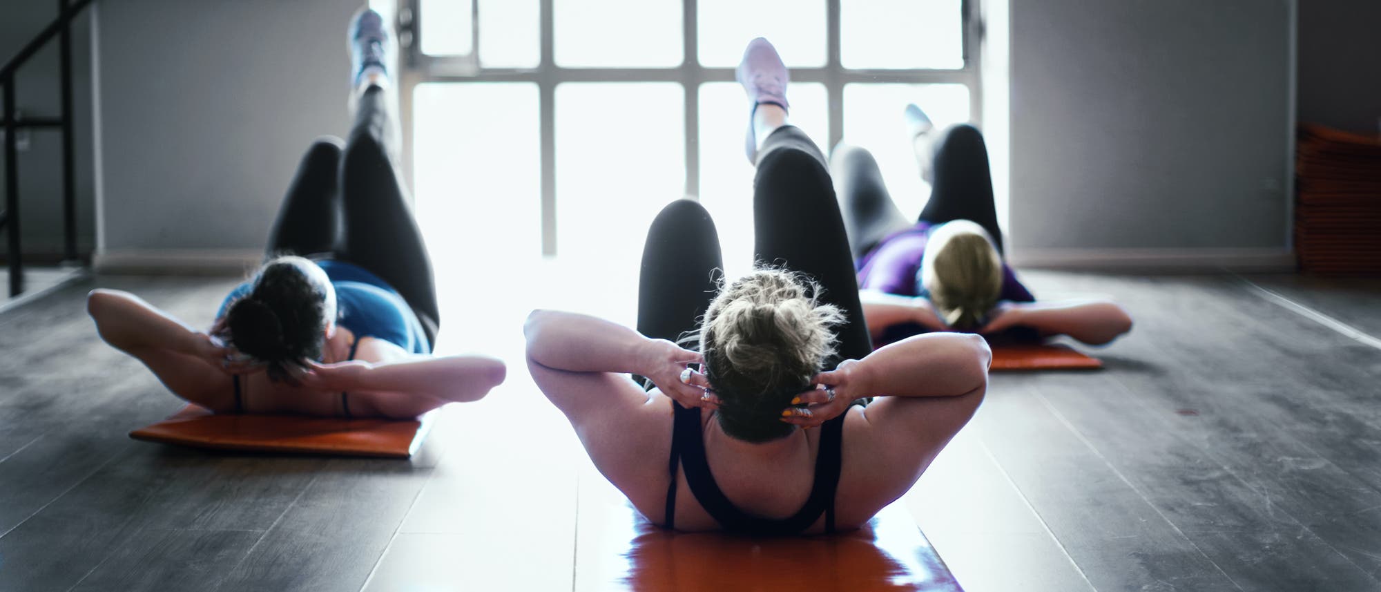 Drei Frauen machen Fitnessübungen in einem Trainingsraum Drei Frauen machen Fitnessübungen in einem Trainingsraum