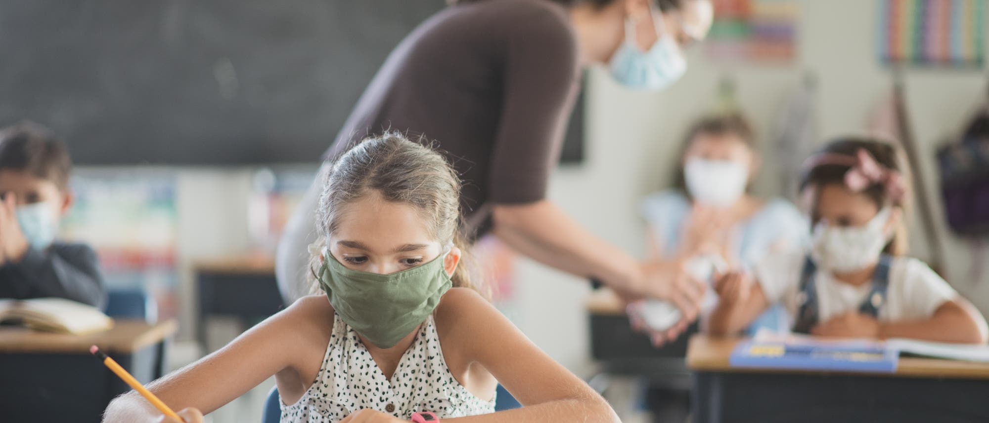 Schülerinnen und Schüler mit Masken in einem Klassenraum. Schülerinnen und Schüler mit Masken in einem Klassenraum.