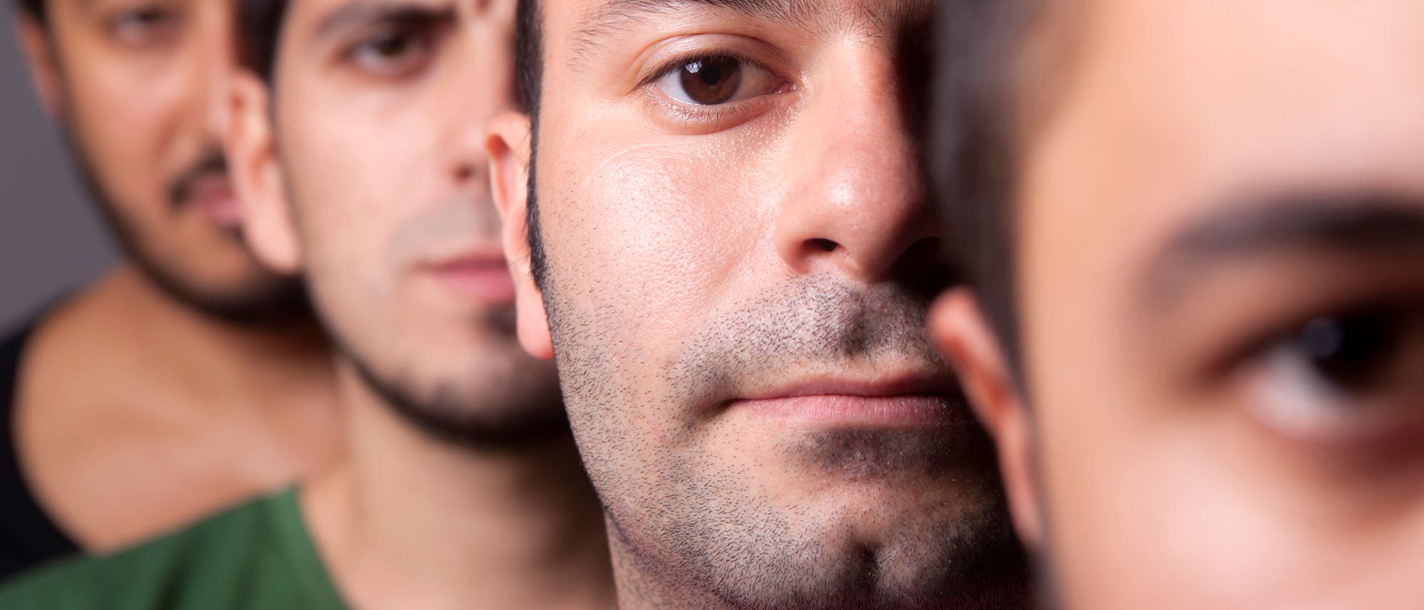 Gesichter von Männern, die hintereinander in einer Reihe stehen Gesichter von Männern, die hintereinander in einer Reihe stehen