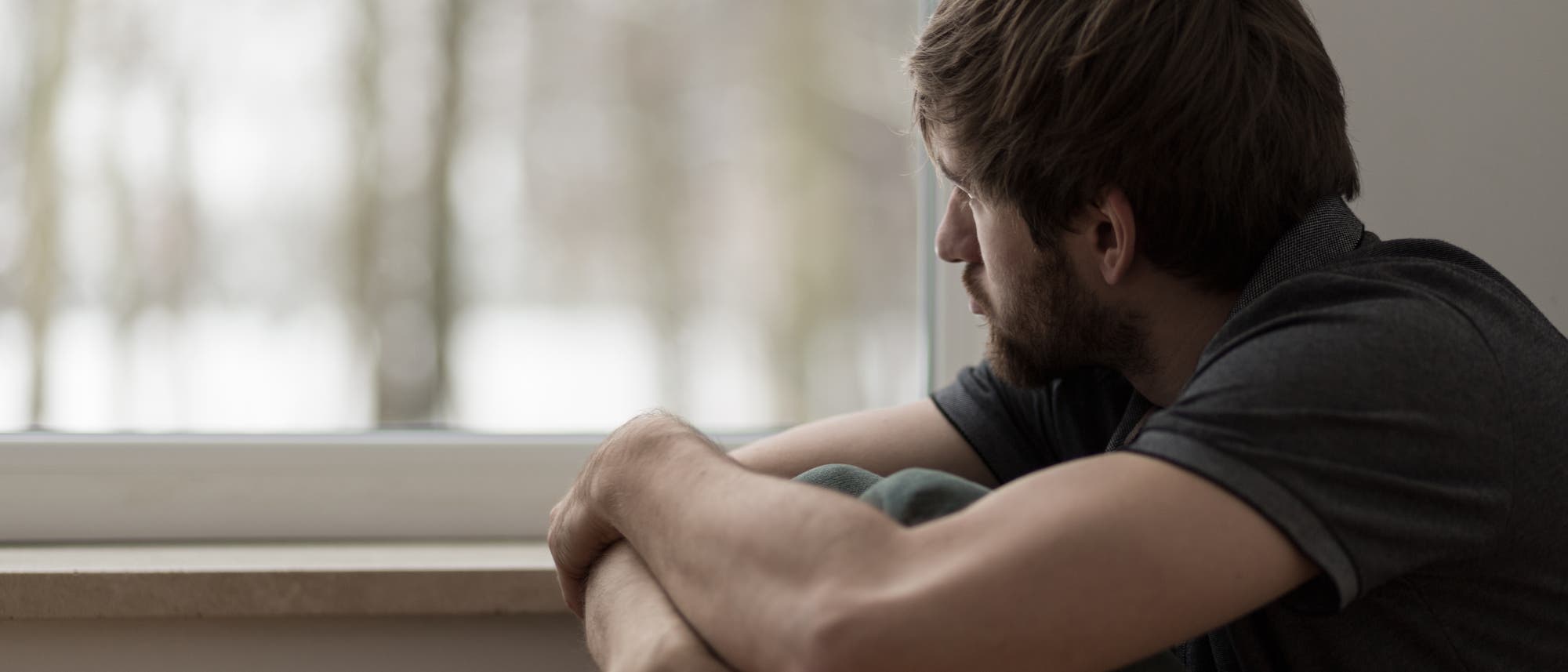 Junger Mann allein am Fenster Junger Mann allein am Fenster