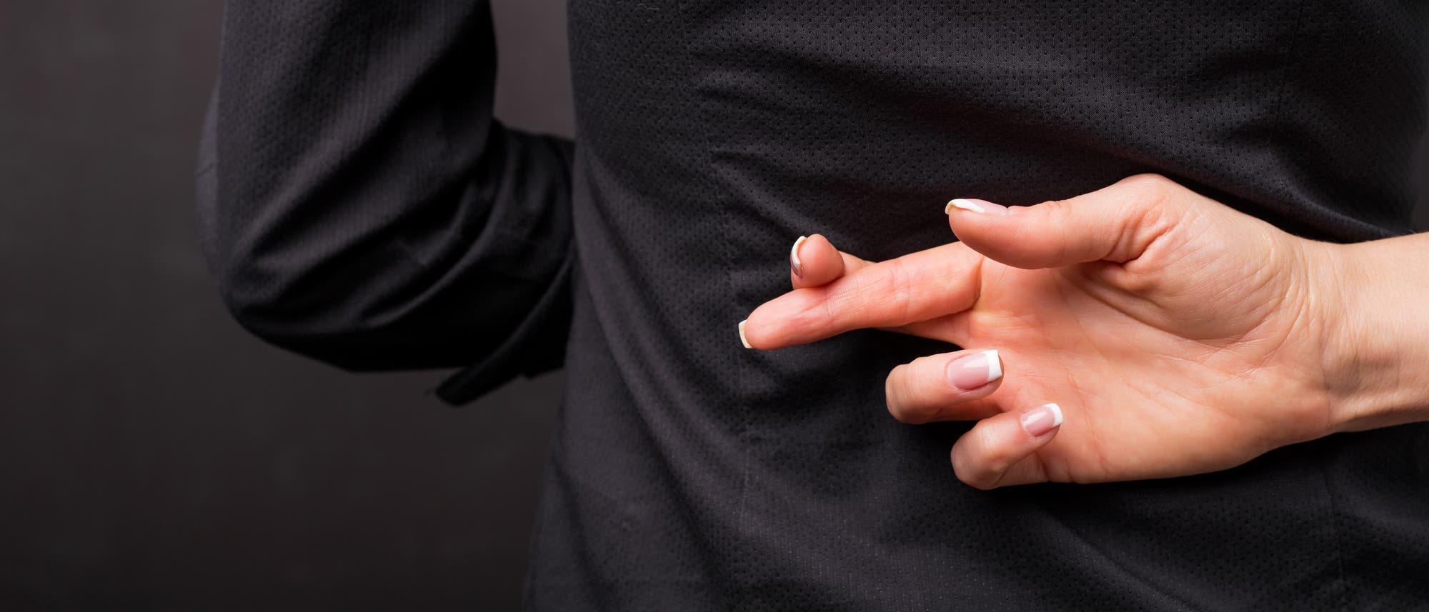 Frau kreuzt die Finger hinter dem Rücken Frau kreuzt die Finger hinter dem Rücken