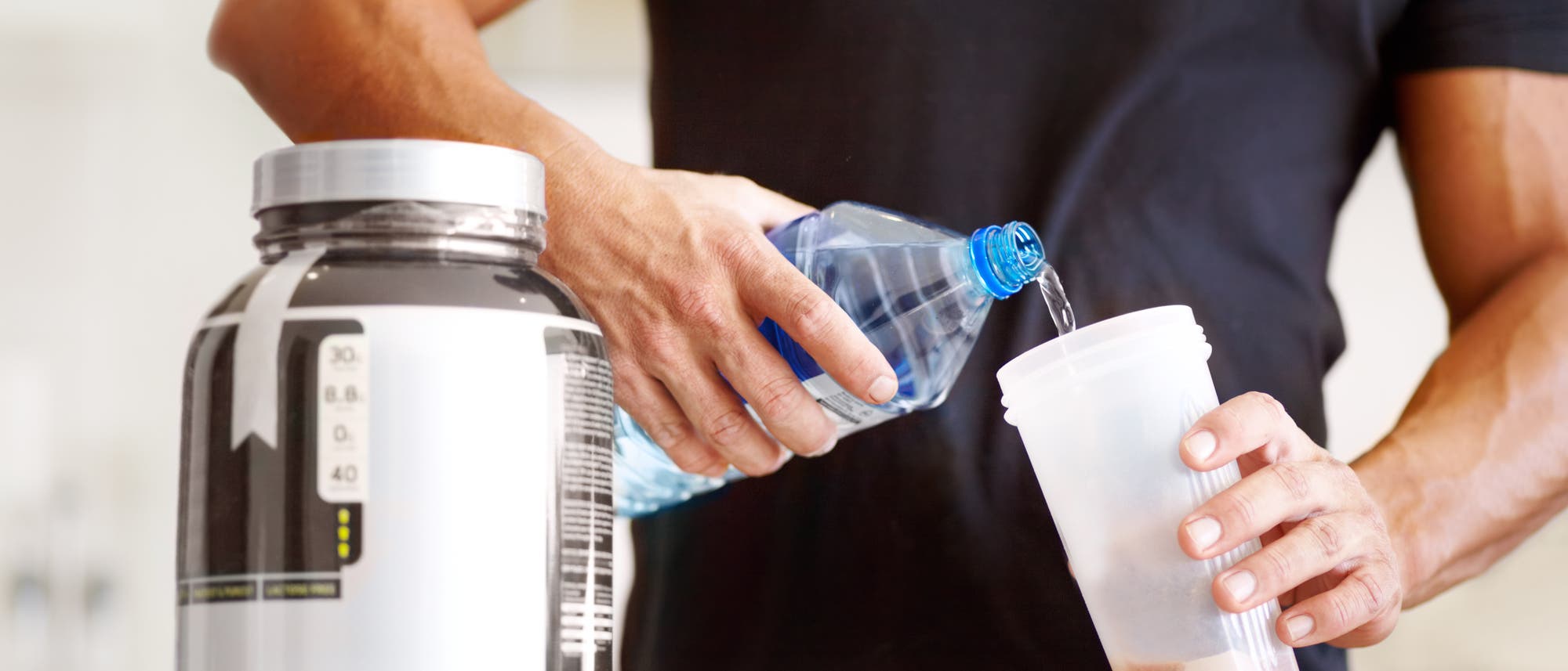Kraftsportler bereitet sich einen Proteindrink zu Kraftsportler bereitet sich einen Proteindrink zu