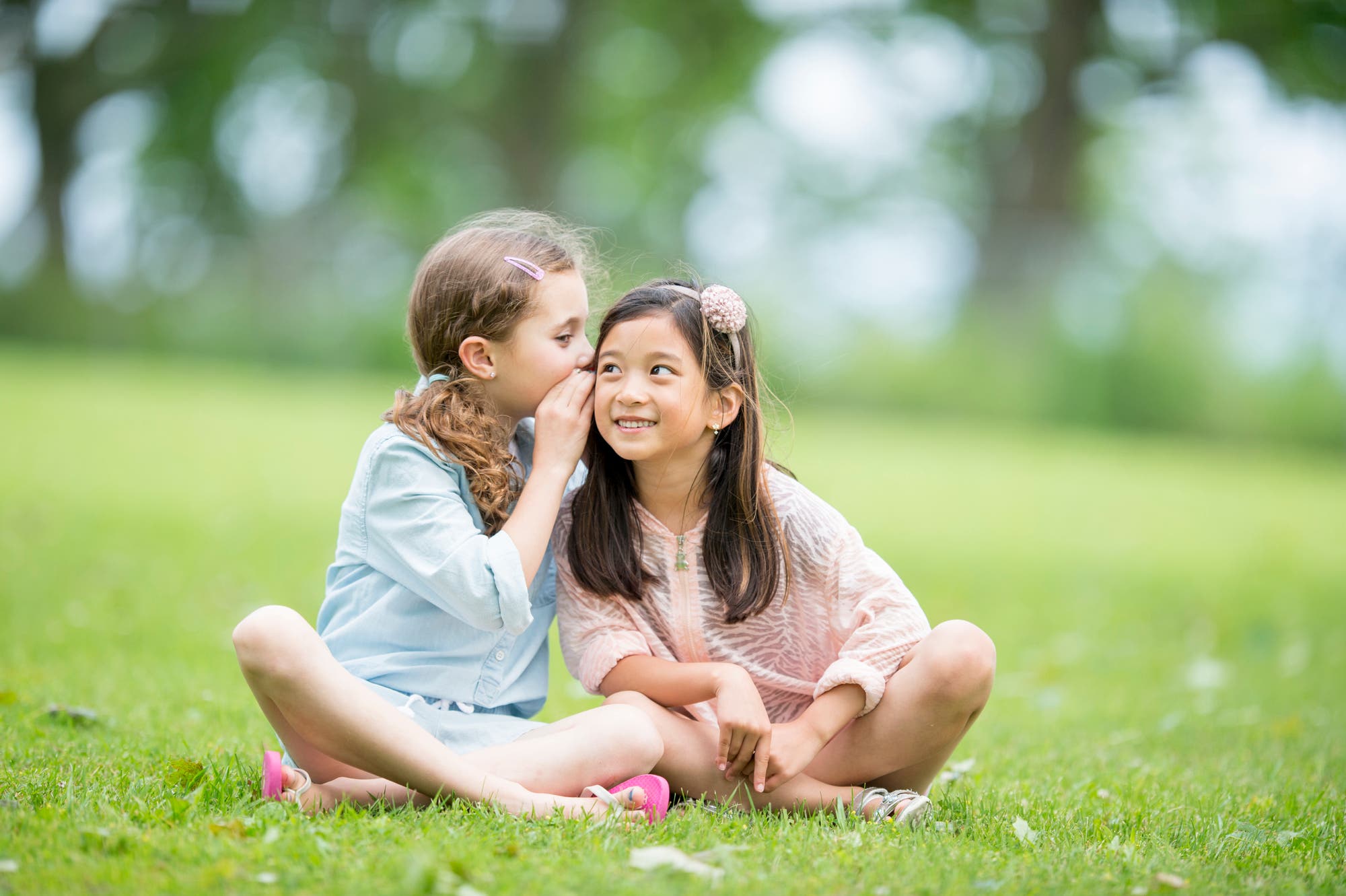 Una niña le susurra algo al oído a la otra