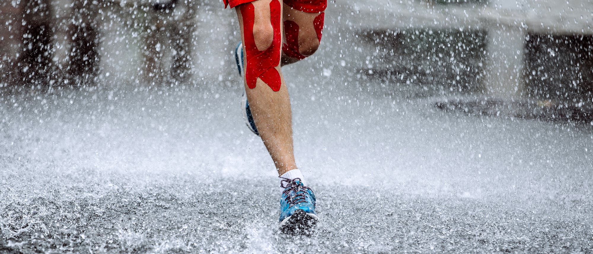 Ein Mann mit Kinesiotapes läuft durch den Regen Ein Mann mit Kinesiotapes läuft durch den Regen