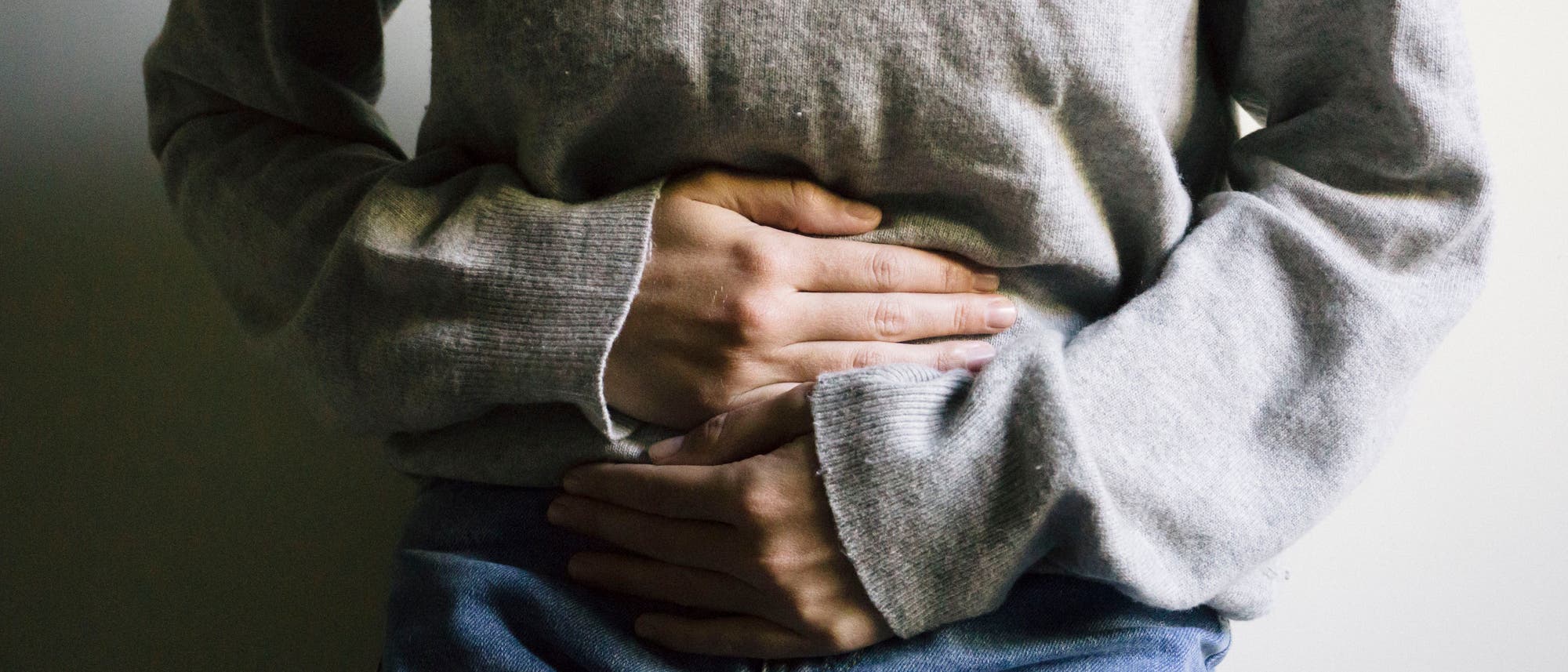 Eine Frau hält sich mit beiden Händen den Bauch Eine Frau hält sich mit beiden Händen den Bauch