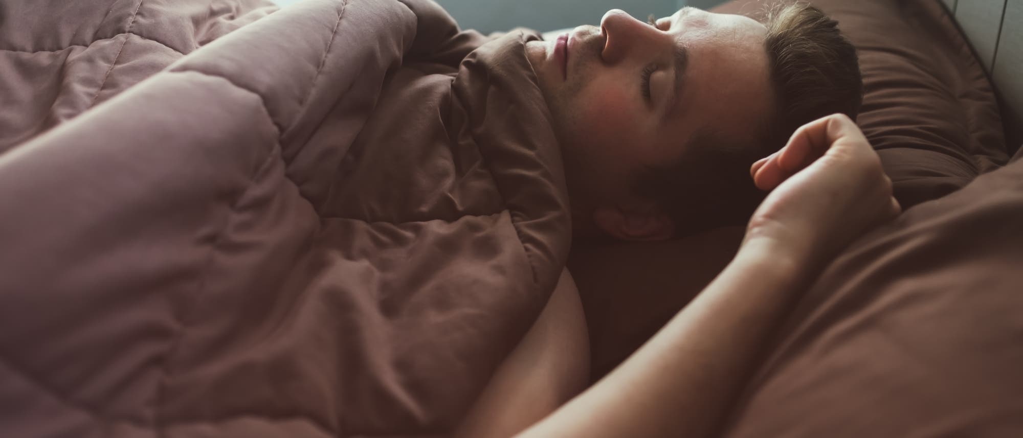 Blick auf eine im Bett liegende schlafende Person Blick auf eine im Bett liegende schlafende Person