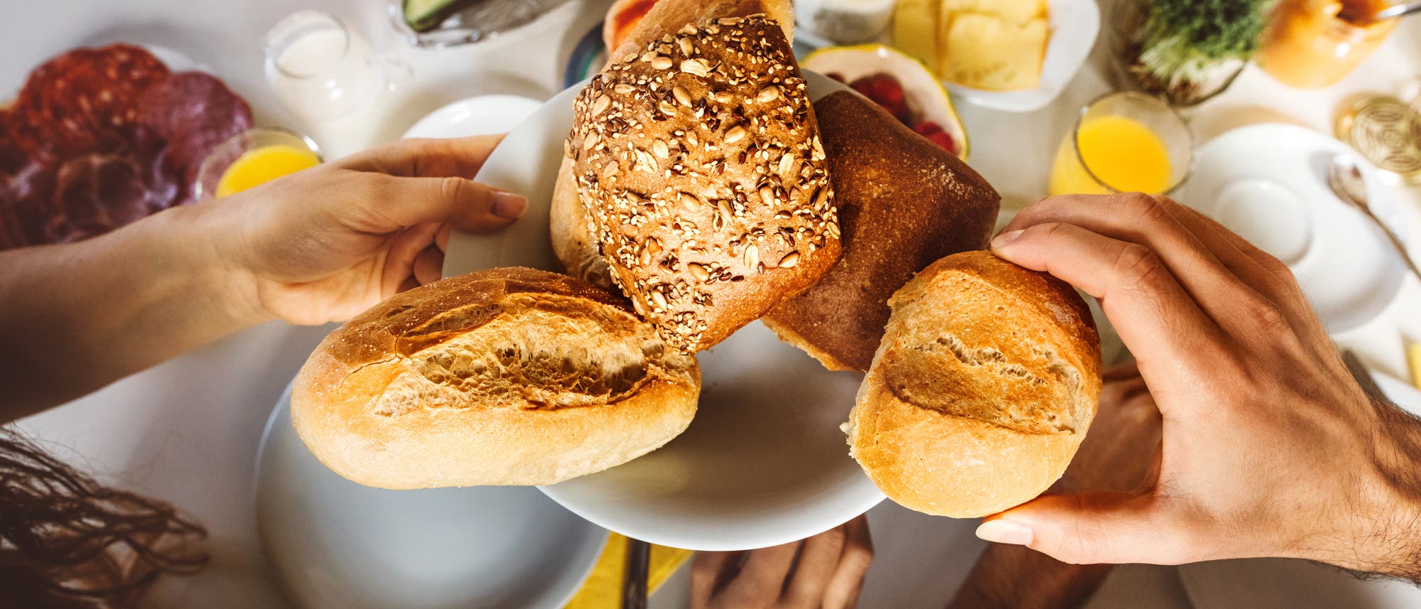 Teller mit Brot und Brötchen am Frühstückstisch Teller mit Brot und Brötchen am Frühstückstisch