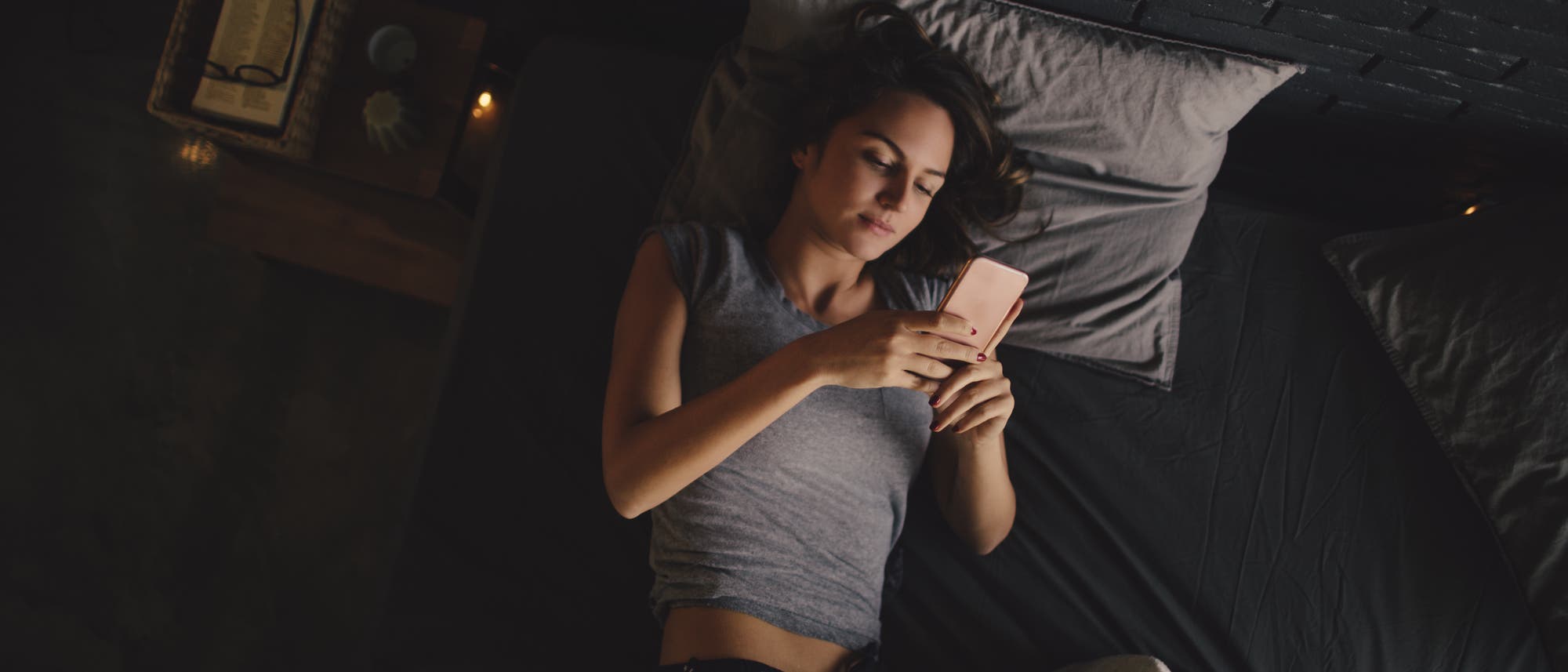 Frau liegt mit Smartphone im Bett Frau liegt mit Smartphone im Bett