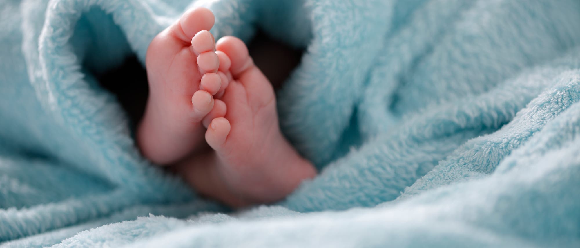 Babyfüße schauen aus einer Decke heraus. Babyfüße schauen aus einer Decke heraus.