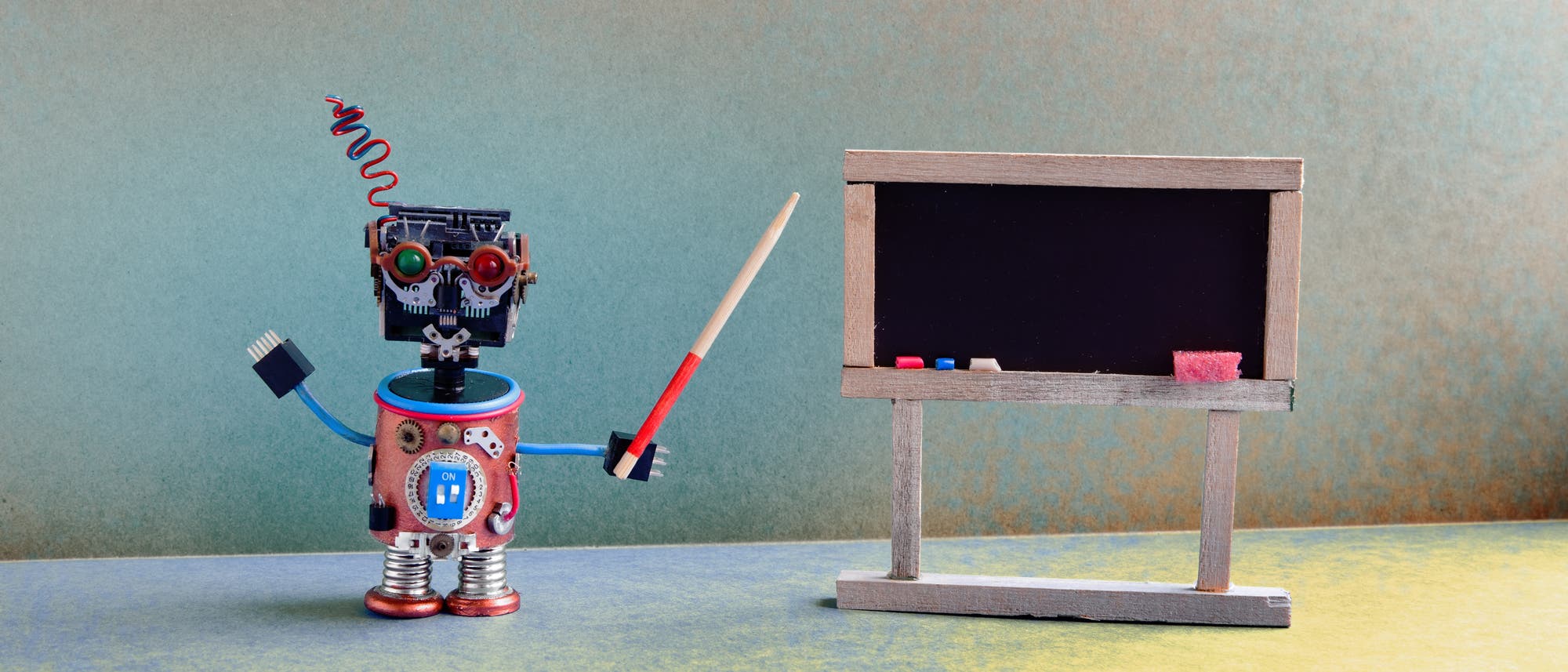 Ein kleiner Roboter steht vor einer Tafel Ein kleiner Roboter steht vor einer Tafel