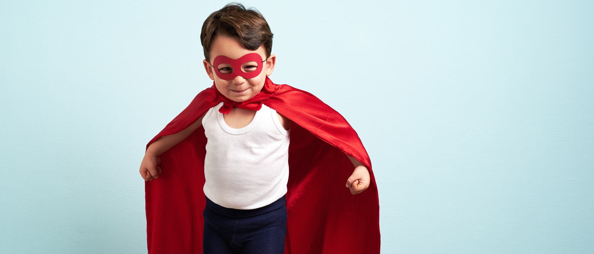 Ein Kind trägt eine Maske und ein rotes Cape. Es sieht aus wie ein Superheld. Ein Kind trägt eine Maske und ein rotes Cape. Es sieht aus wie ein Superheld.