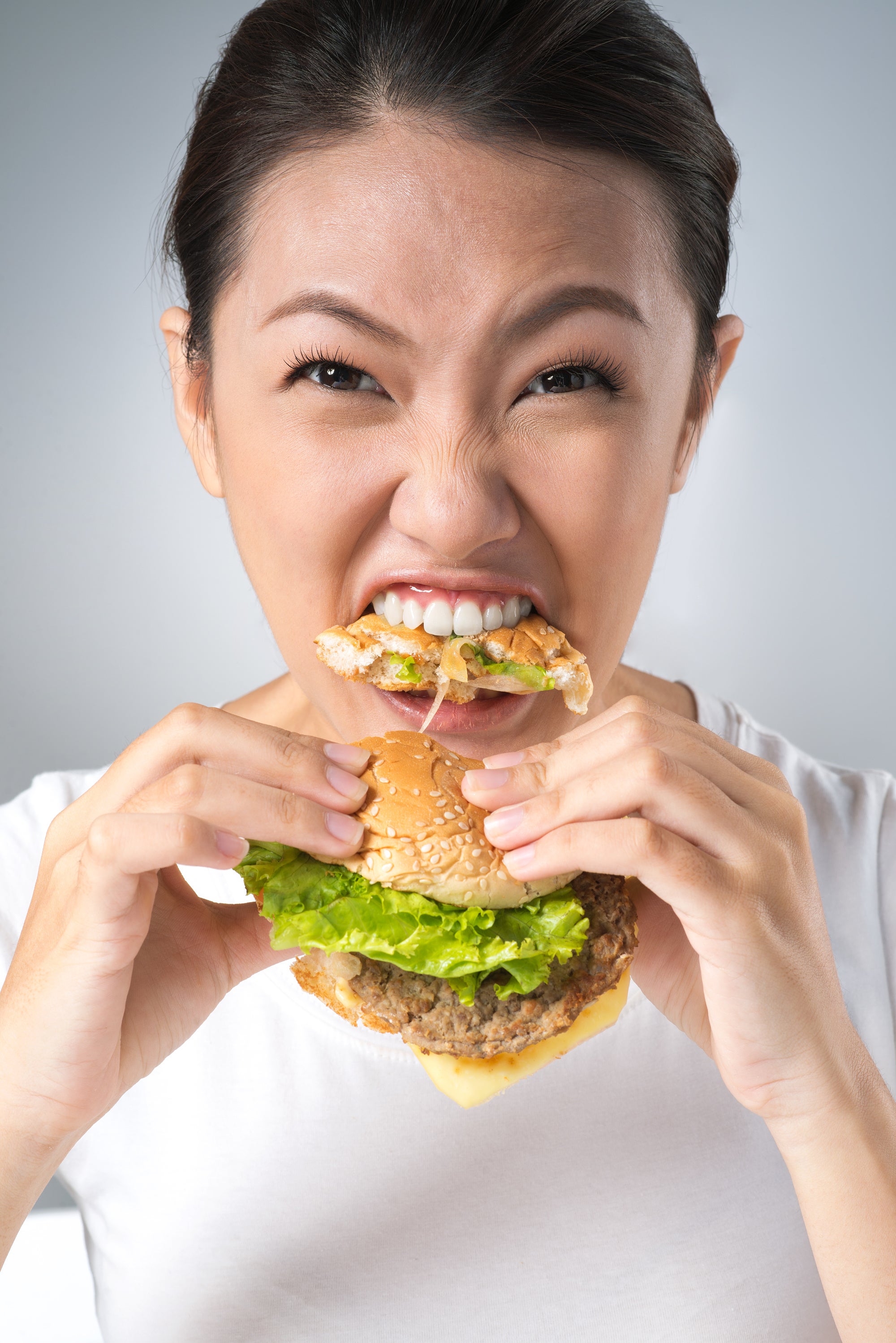 Frau beisst kräftig in einen Cheeseburger Frau beisst kräftig in einen Cheeseburger