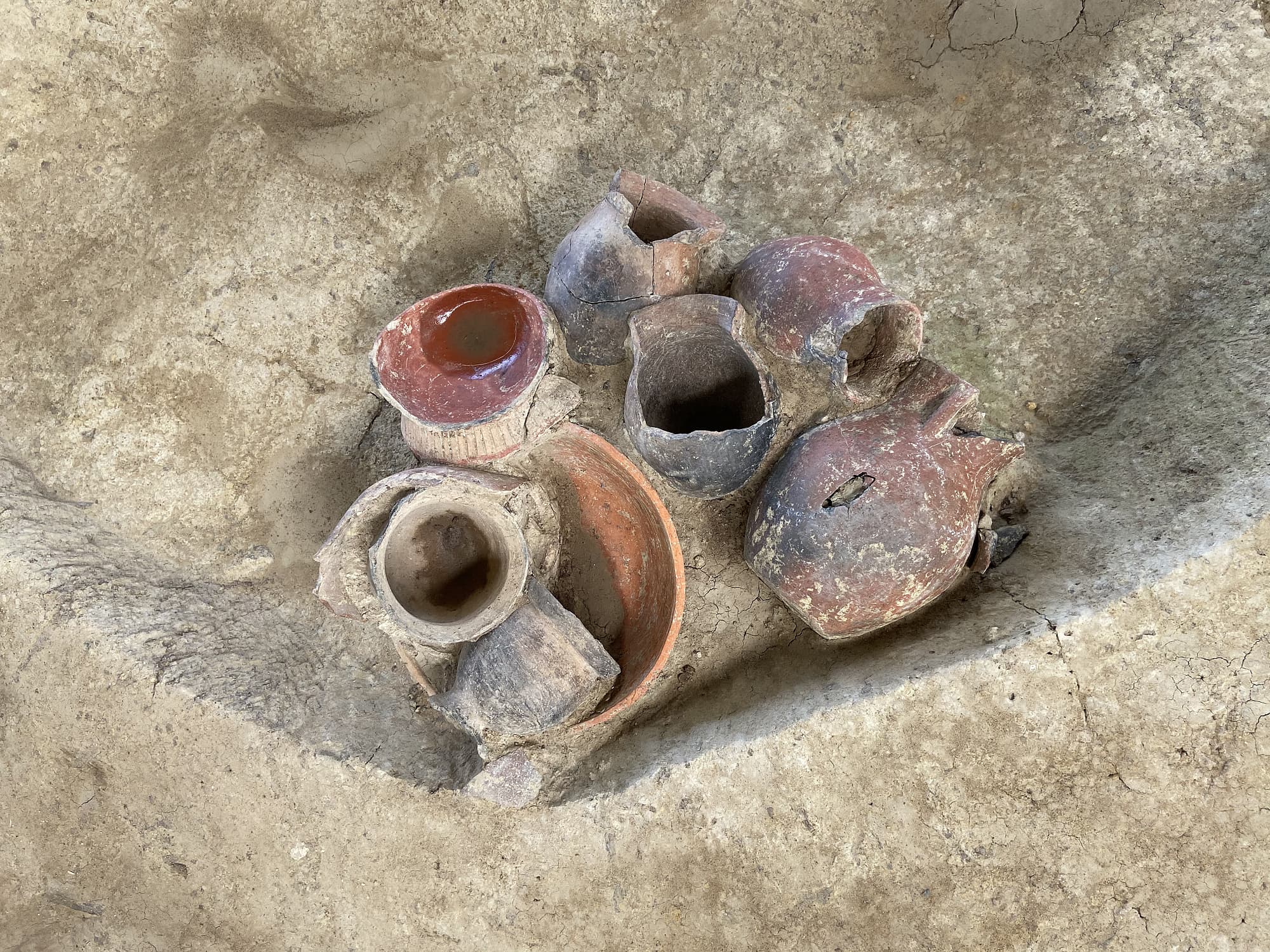 Mehrere rötliche Tongefäße, halb ausgegraben in hellem Sediment. Mehrere rötliche Tongefäße, halb ausgegraben in hellem Sediment.