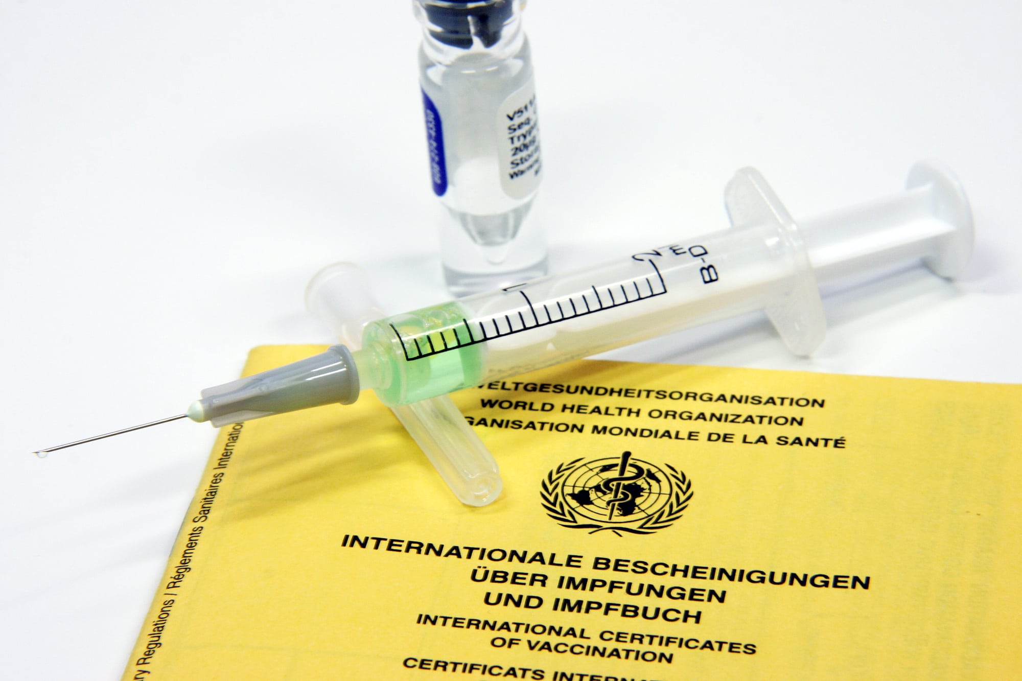 Spritze liegt auf Impfpass Spritze liegt auf Impfpass