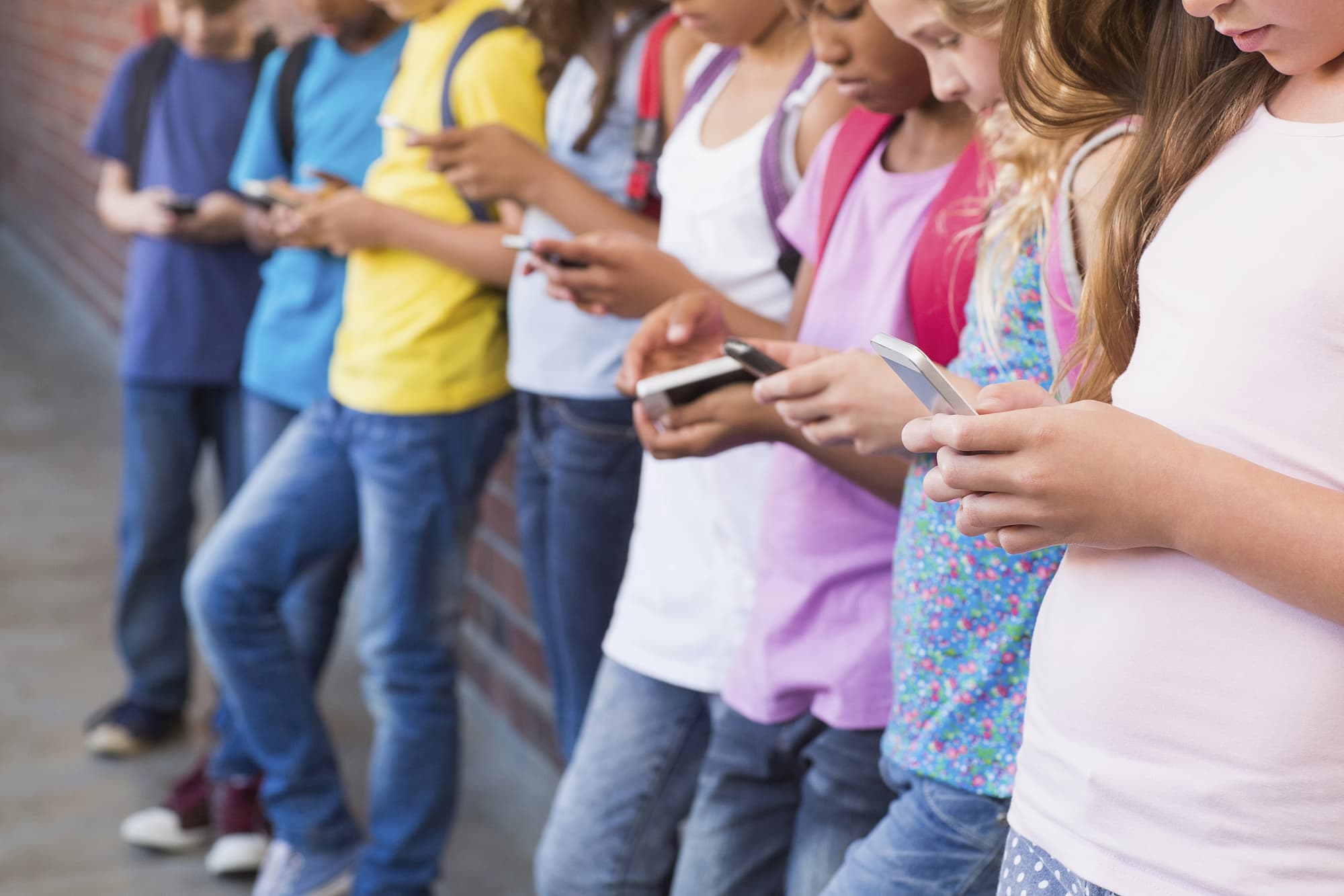 Eine Reihe Schüler mit Smartphones und abgeschnittenen Köpfen Eine Reihe Schüler mit Smartphones und abgeschnittenen Köpfen