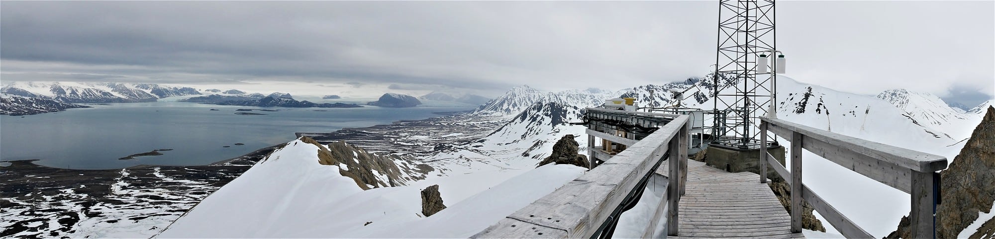 Panoramaaufnahme von der Terrasse des Zeppelin-Bergs über Ny-Ålesund und den Fjord auf Berge und Gletscher am anderen Ufer. Panoramaaufnahme von der Terrasse des Zeppelin-Bergs über Ny-Ålesund und den Fjord auf Berge und Gletscher am anderen Ufer.