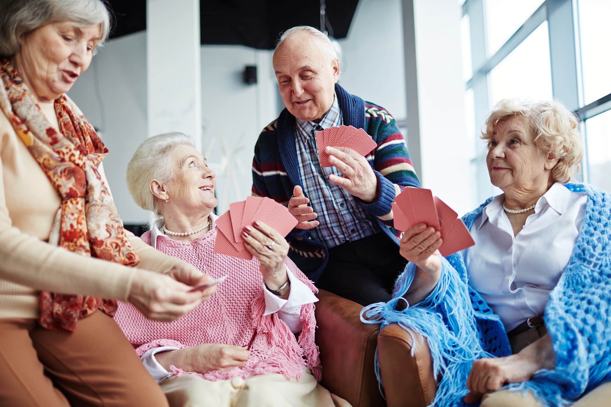 Seniorinnen spielen mit altem Herrn Karten Seniorinnen spielen mit altem Herrn Karten