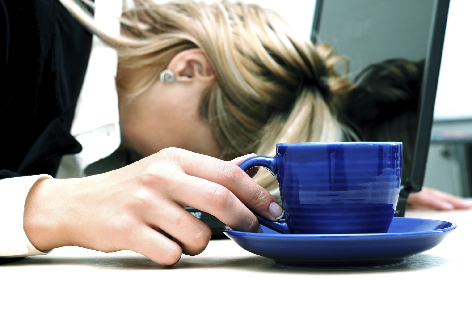 Frau sinkt trotz Kaffee auf ihrem Notebook zusammen Frau sinkt trotz Kaffee auf ihrem Notebook zusammen