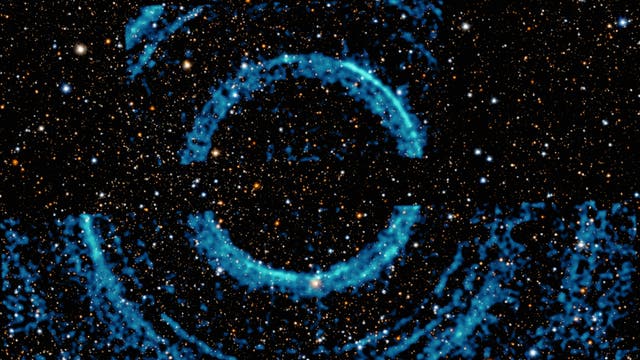 Röntgenechos um V404 Cygni, dargestellt als blaue Ringe auf einer Abbildung des Sternenhimmels im sichtbaren Licht.